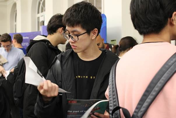 1A student studies a floorplan in a crowded face-to-face Careers Fair